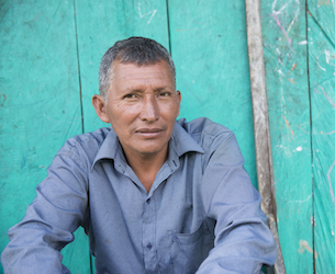 Man sitting against a wall looking at the camera